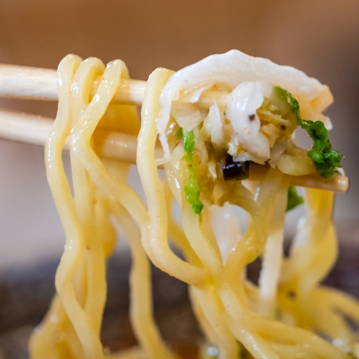 close up of chopsticks holding ramen